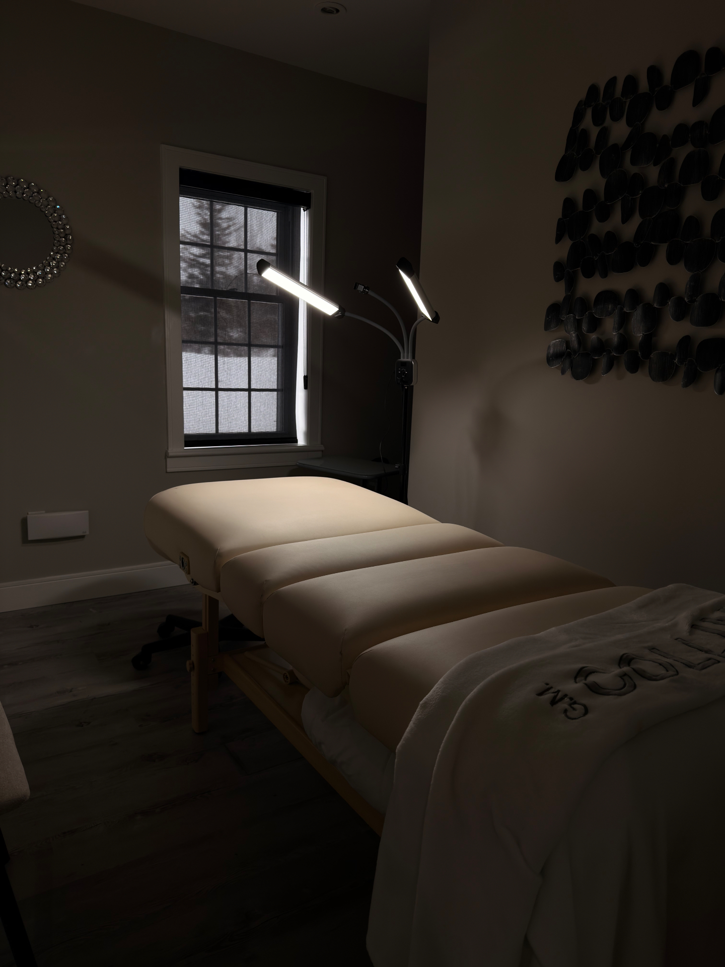A quiet treatment room at H.D. Esthetics — a cream spa bed lit by soft task lighting