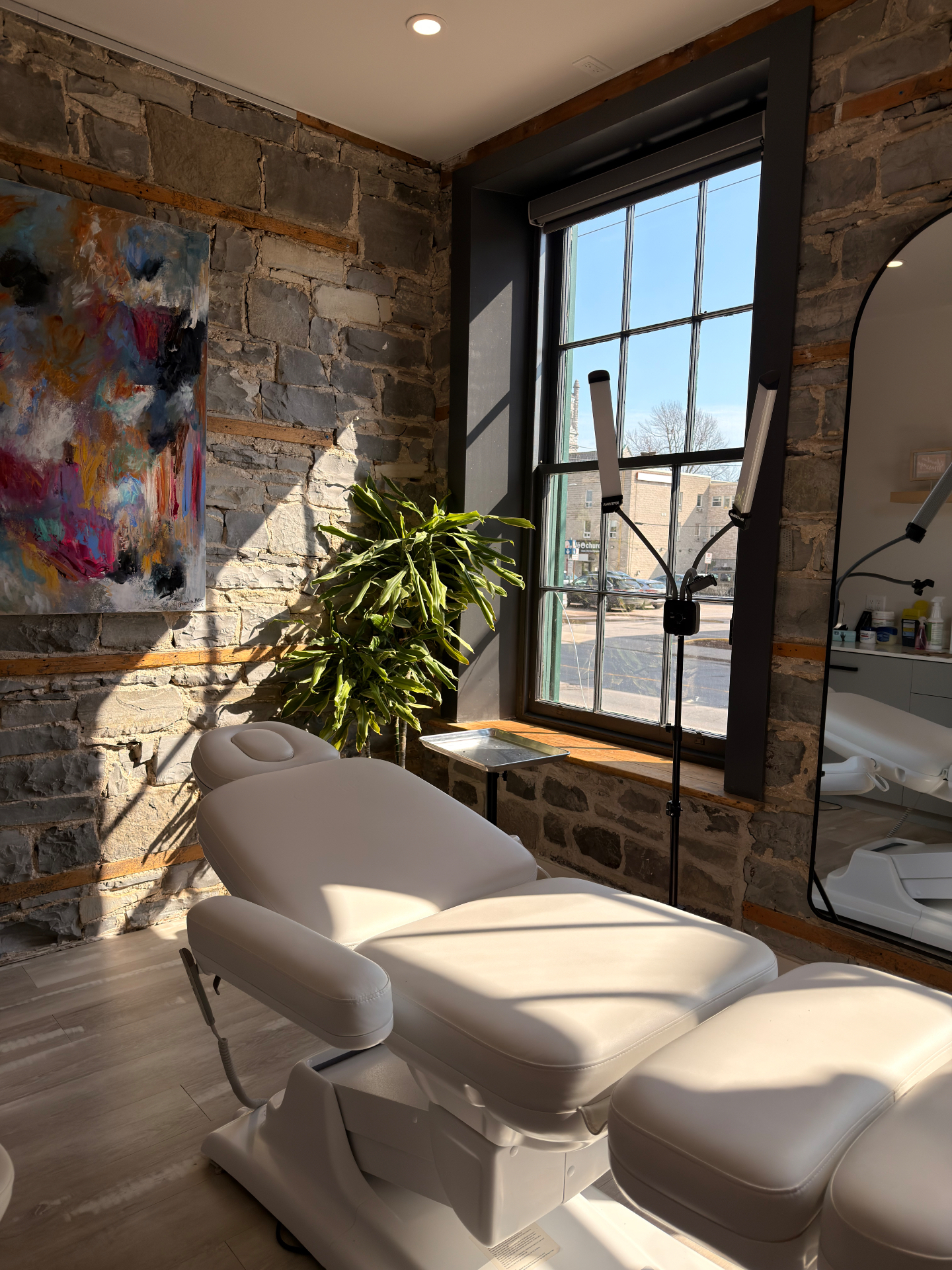 Bright, sunlit treatment studio with stone walls and a comfortable treatment bed